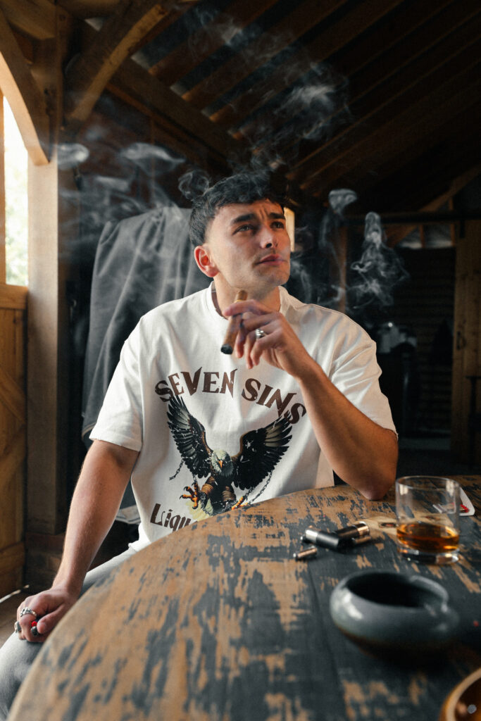 front of seven sins, liquor guns & ammo white t-shirt cigar